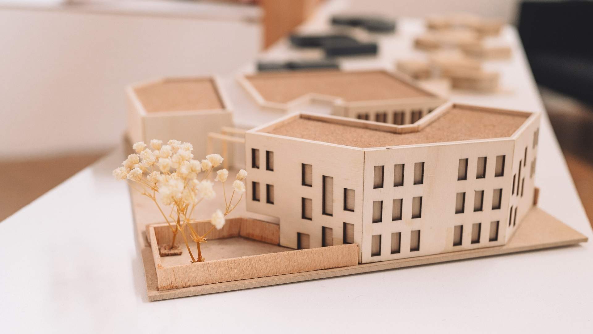 A replica office building made from wood sits on a white desk