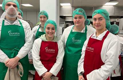 Abigail Derry and a group of young adults in white coats, aprons and hair nets pose for a photograph