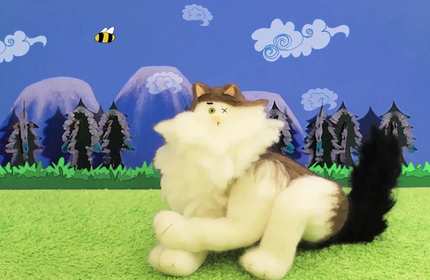 A toy cat sits in front of a painted background