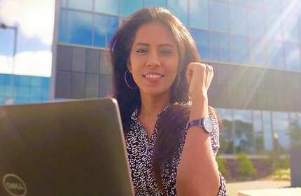 Harshita Manti sat outdoors on a sunny day working on a laptop