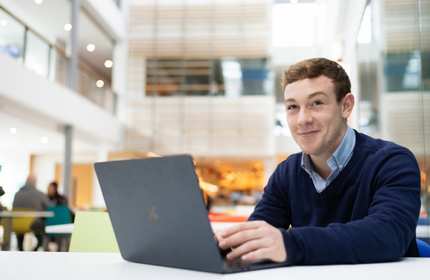 James Charles-White sits at a desk working from a laptop