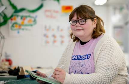 Morgan Bebb looks up from a digital tablet they are holding