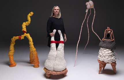 Sam Lucas stands with intricate clay sculptures that they has crafted