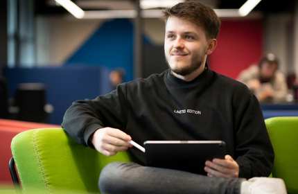 A man comfortably sitting on a couch, using a tablet, illustrating a moment of leisure and technology interaction.