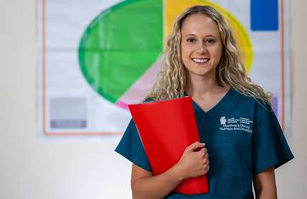 Tayla Smith stands holding a red plastic folder