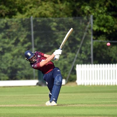 A cricket player swings their bat at the ball during a match