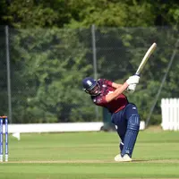 A cricket player swings their bat at the ball during a match