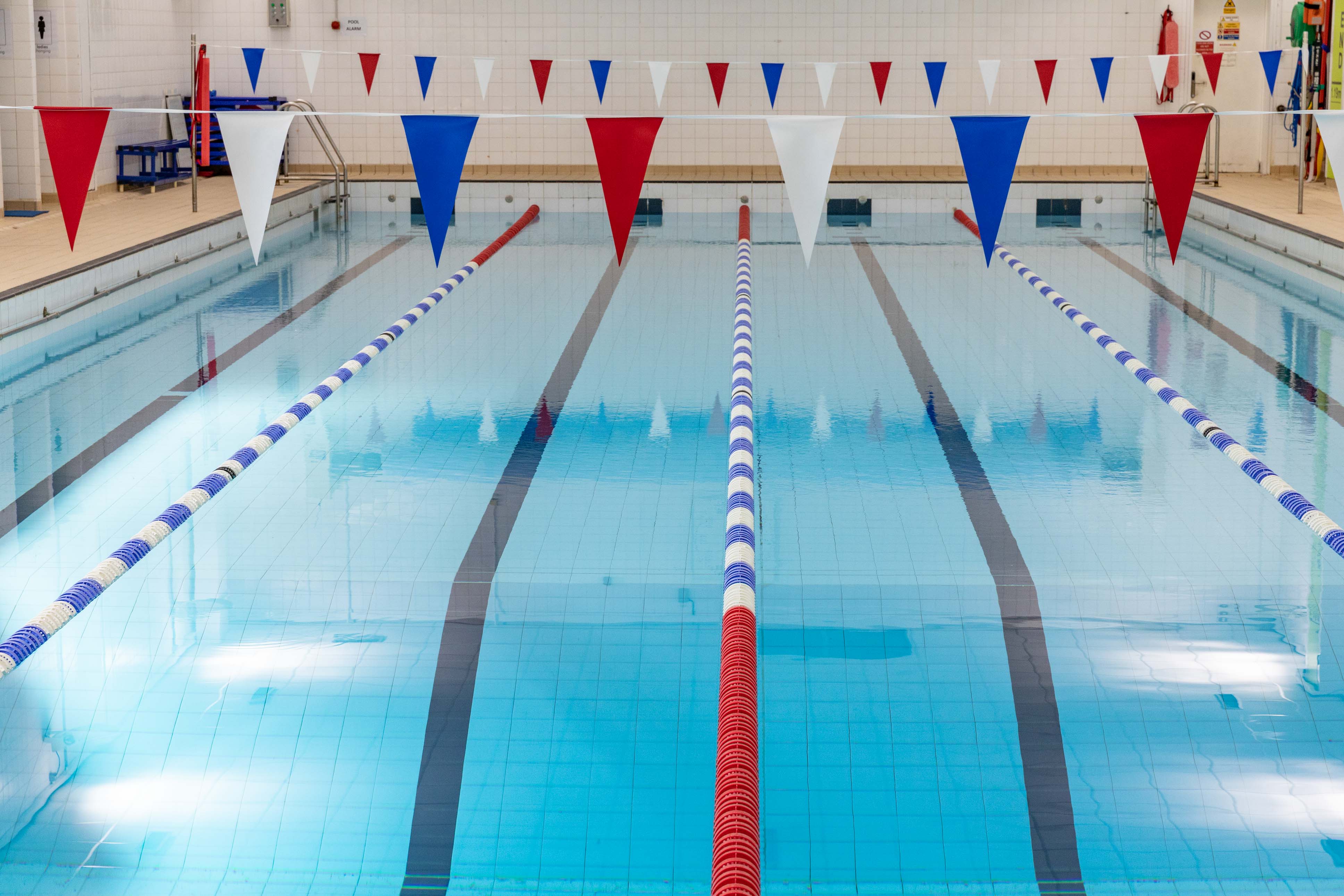 A swimming pool with race lanes and decorative bunting overhead