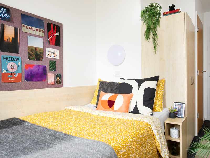 A decorated bedroom complete with posters hanging on a display board and made up bed
