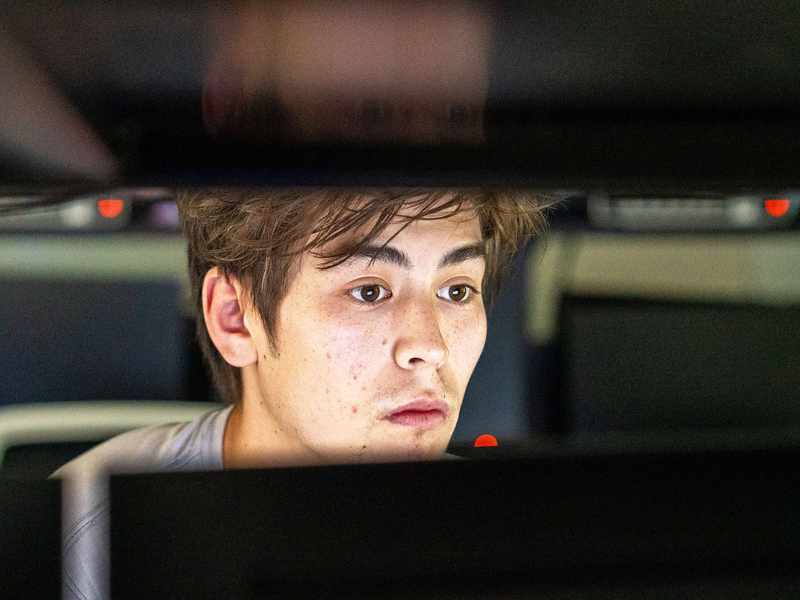 A close-up of a person looking at a computer monitor. Their face is lit from the light of the screen.