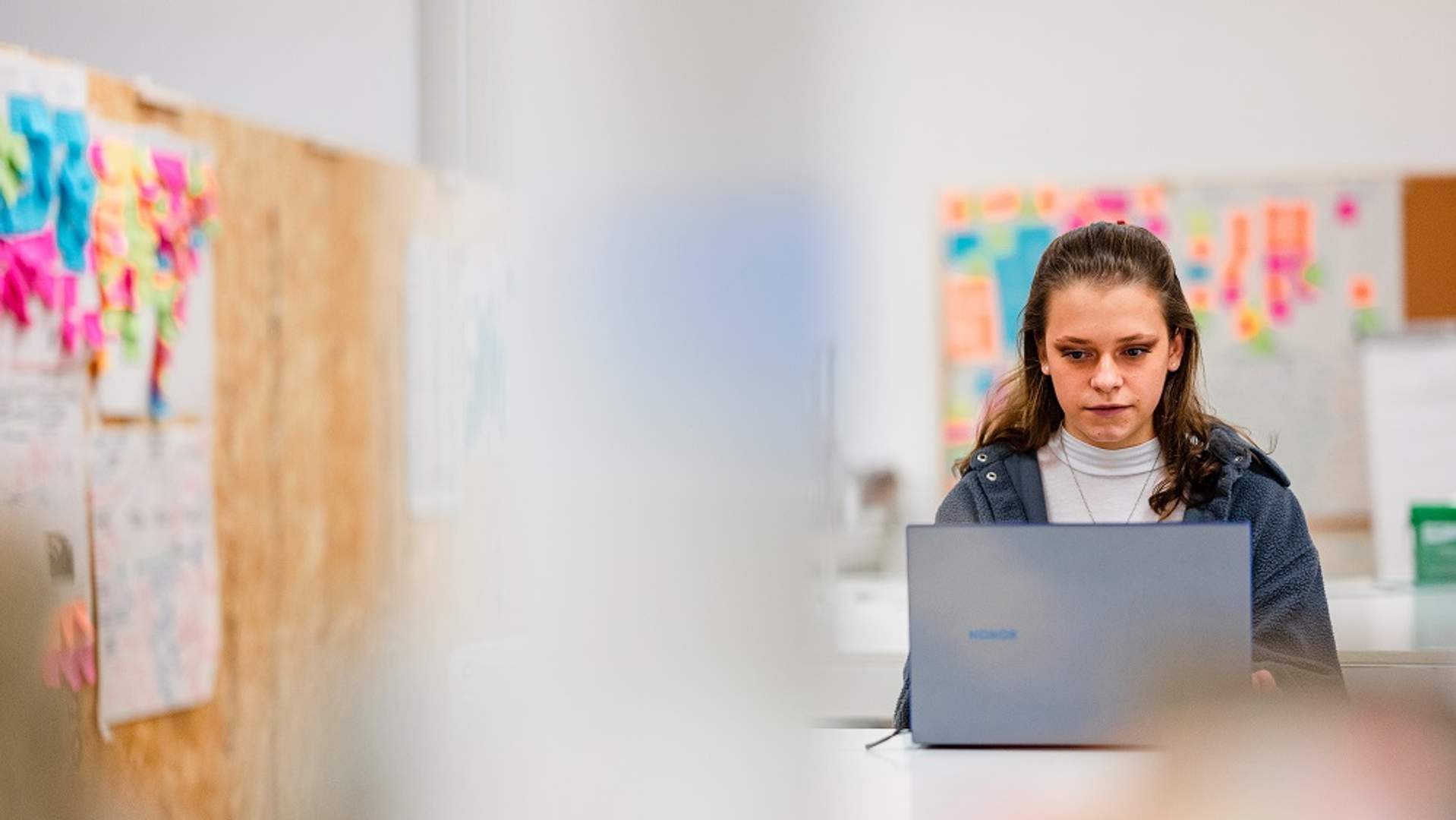 A young adult works from a laptop in an arts workspace