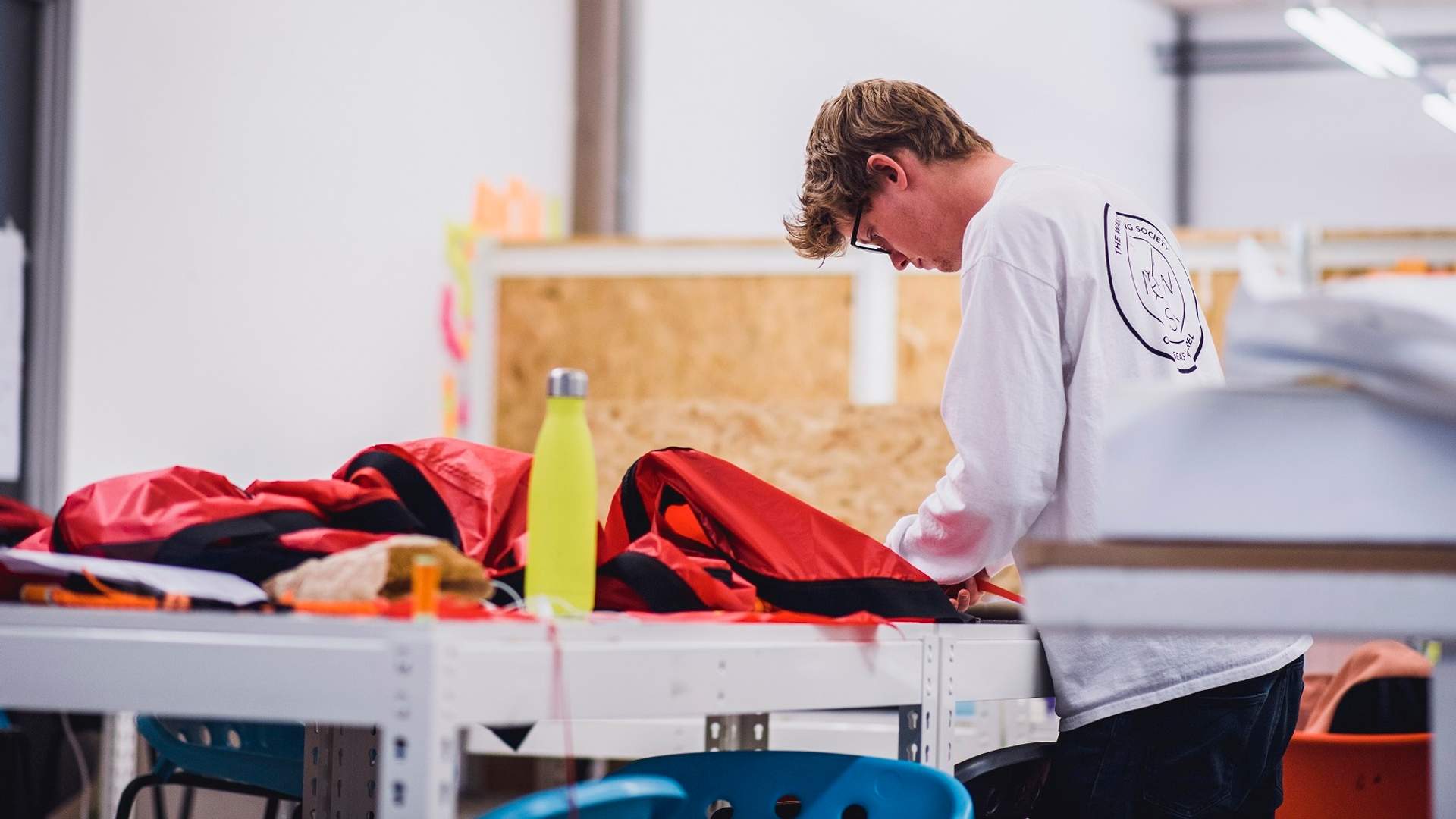A student works on a large piece of red fabric in an art and design workshop