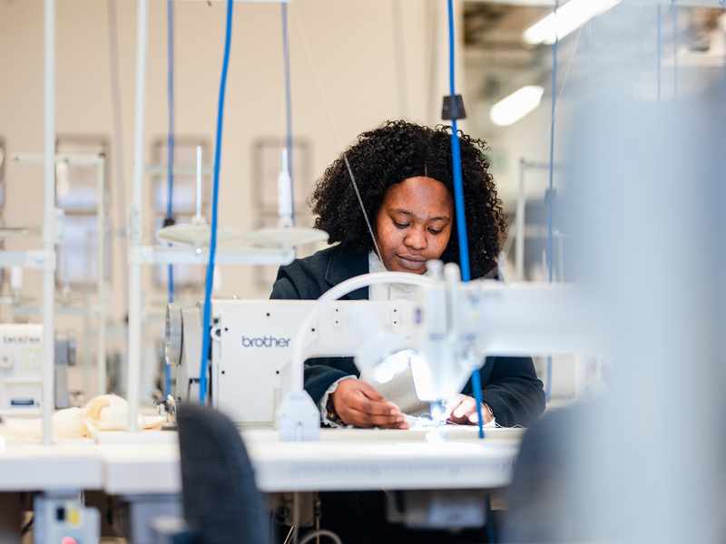 A young woman works at a sewing machine
