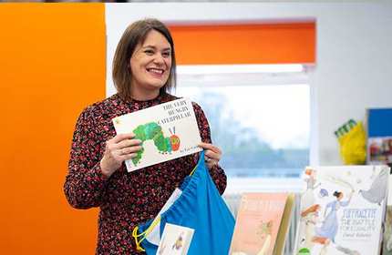 Teacher displays a book with both hands
