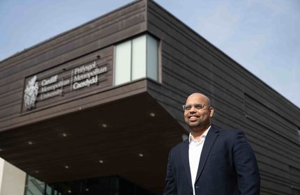 A School of Management staff member stands outside the School of Management building