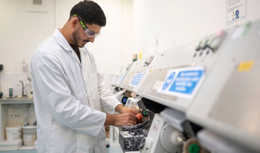 A young adult in white laboratory uniform places his hands in a medical machine
