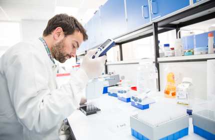 A young man in white laboratory coat conducts research