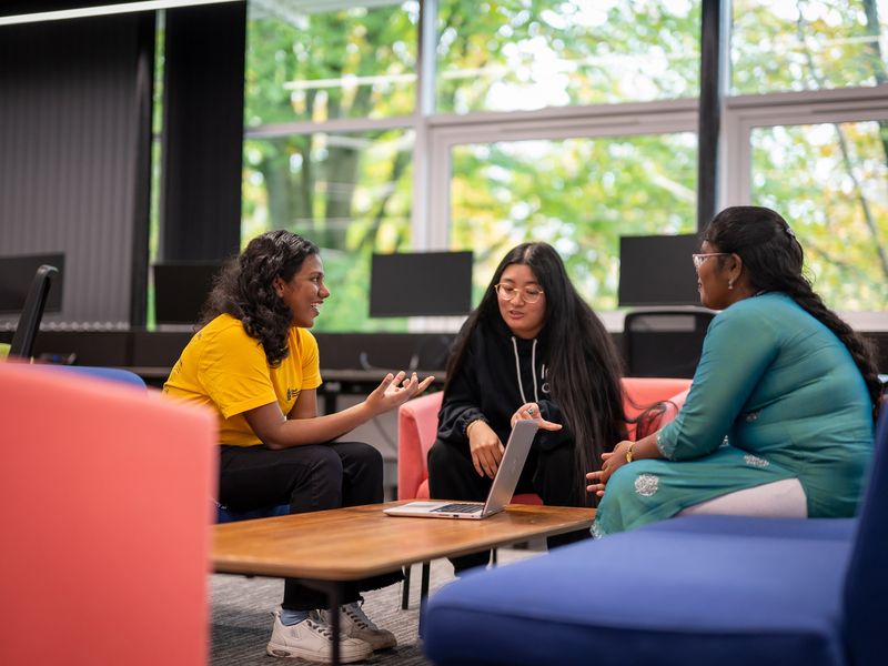 A group of three students sit around a low table for a chat