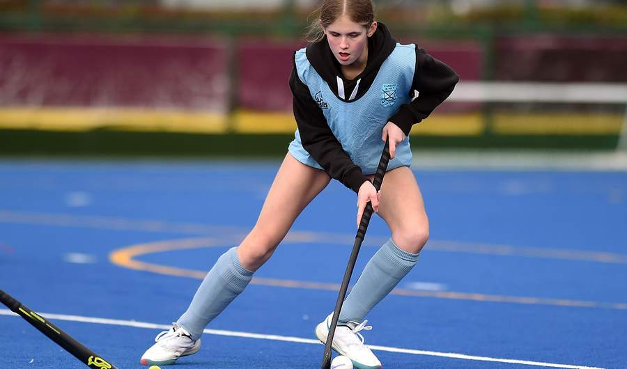 A girl engaged in a field hockey match, demonstrating her athleticism and concentration on the field.