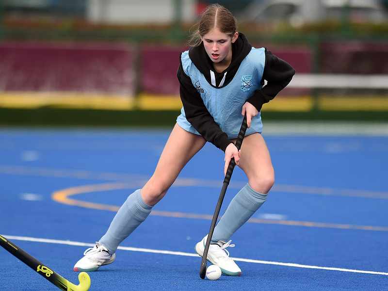 A girl engaged in a field hockey match, demonstrating her athleticism and concentration on the field.