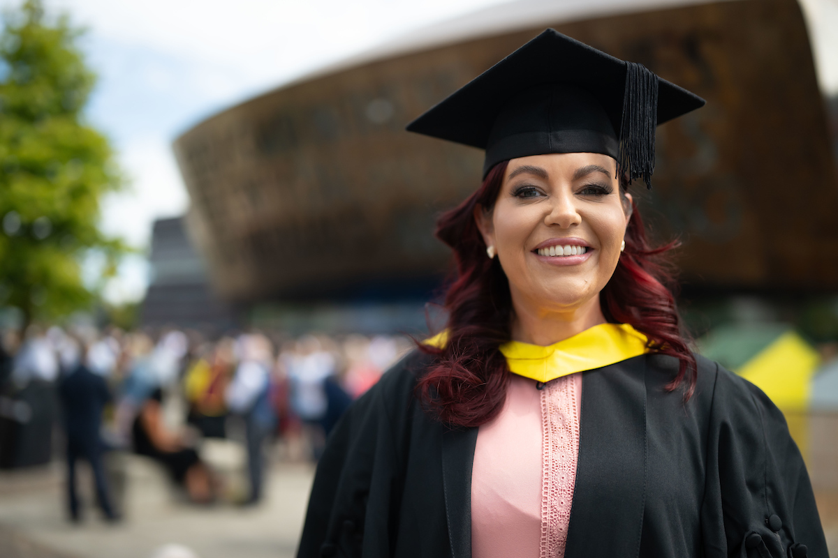 woman proudly wearing a graduation gown and cap, celebrating her academic achievement.
