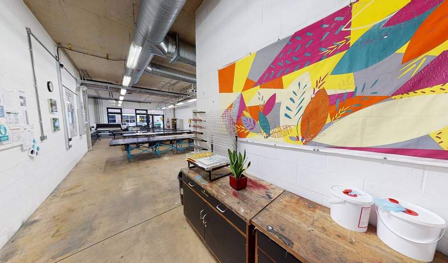 A sideboard beneath a brightly coloured fabric print mounted on a wall