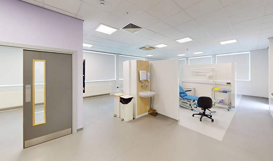 A large white room. In the centre is a partially-walled area with an examination chair.