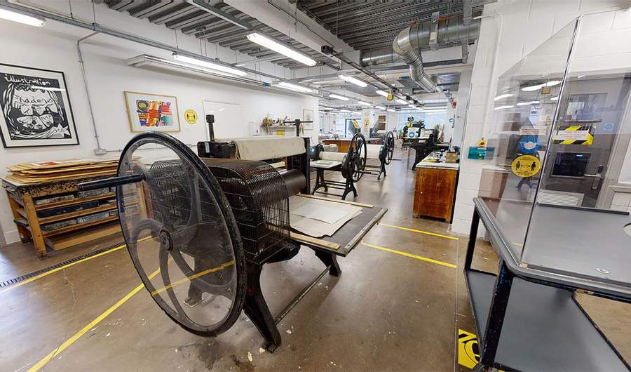 Printing press as the focus of a wide shot of the Printmaking Workshop