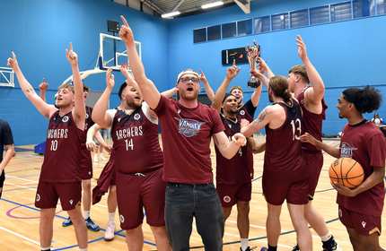 The varsity basketball team celebrates on the court after winning a game