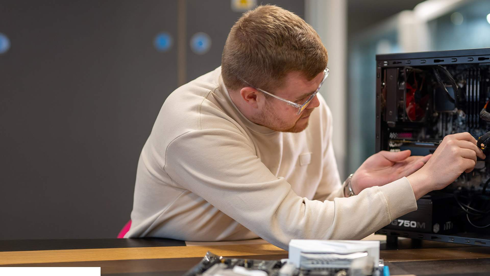 A woman wearing a polka dot jacket smiles while standing in front of a screen displaying a colorful line graph.