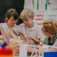 A diverse group of children collaborating on a project, sharing ideas and materials at a table.