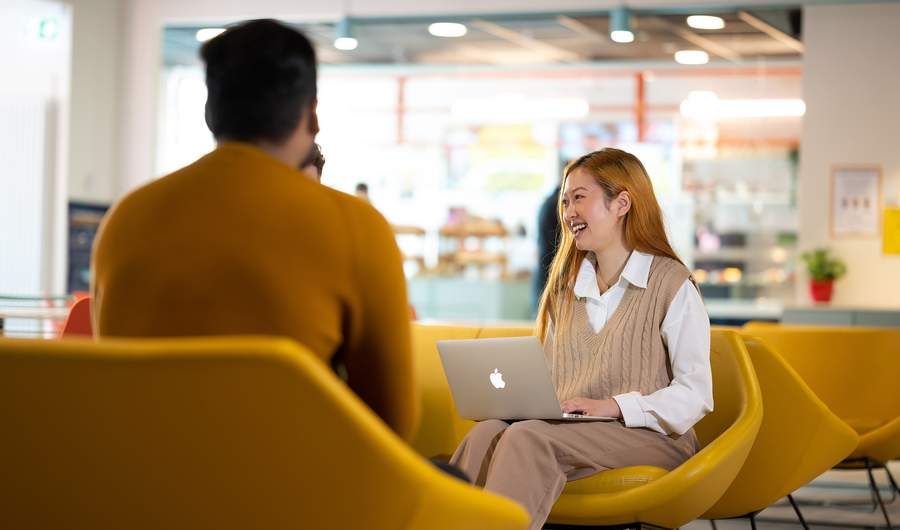 Person with Mac laptop sat on yellow chair