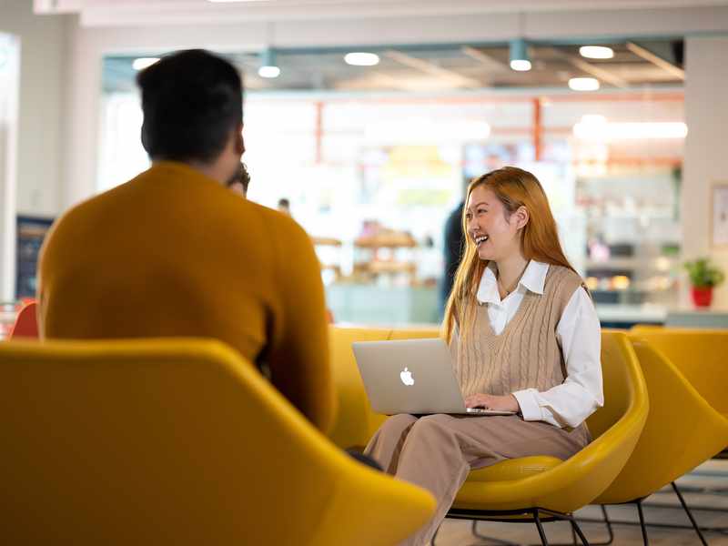 Person with Mac laptop sat on yellow chair