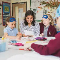 A teacher assists children with their class work, providing guidance and support in a classroom setting.