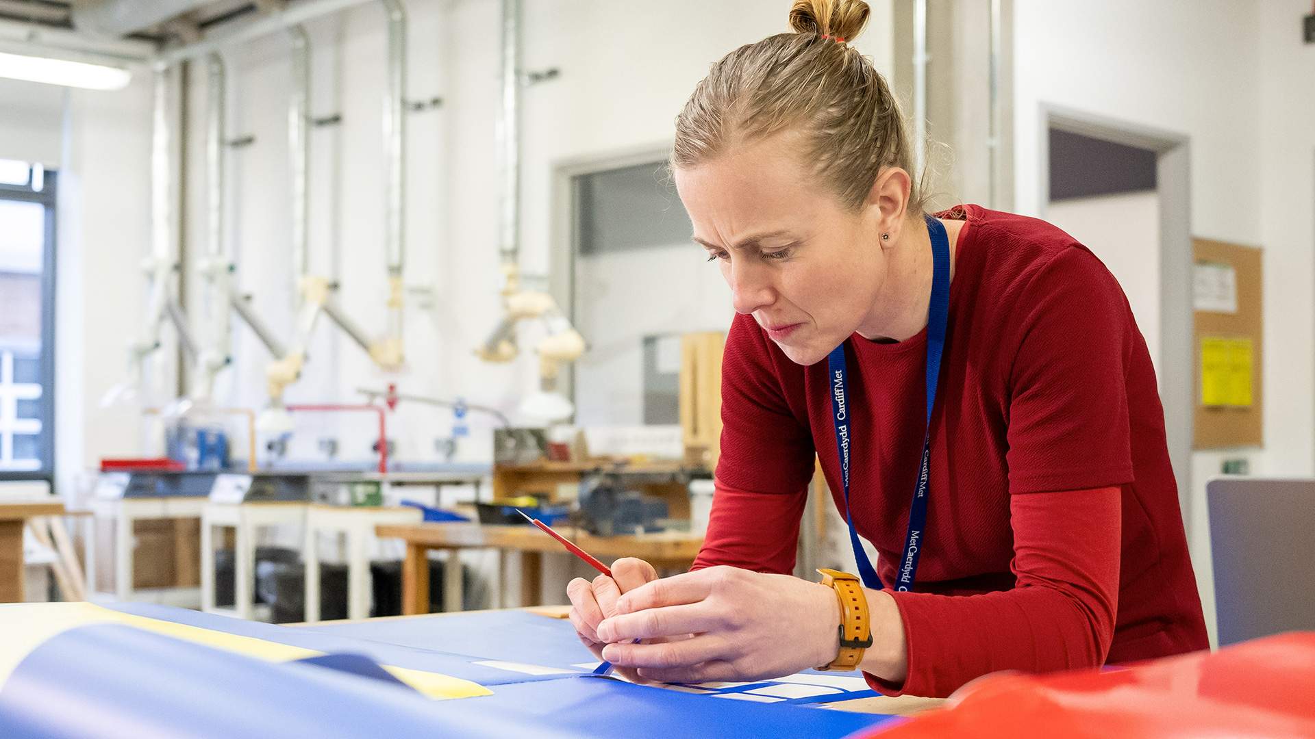 A woman engages in project work at her desk in a classroom, demonstrating concentration and creativity in her task.