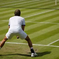 A man is positioned on a tennis court, ready to hit a tennis ball, showcasing athletic posture and concentration.