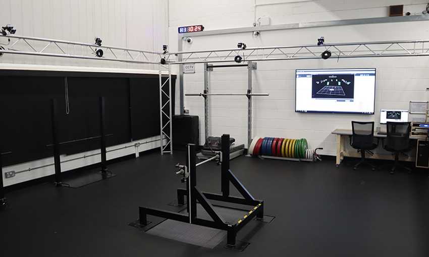A motion capture lab with a force plate, cameras, and a computer screen displaying data analysis.