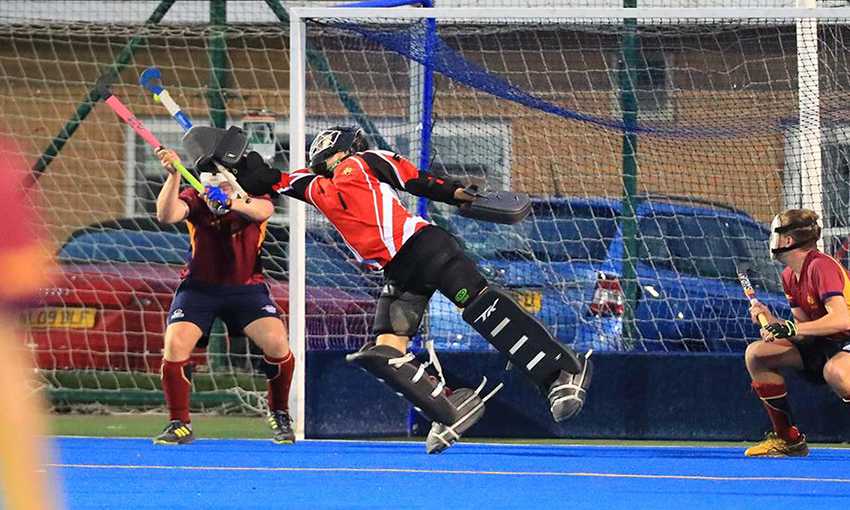 Hockey keeper stretches their stick to make a save during a game of hockey
