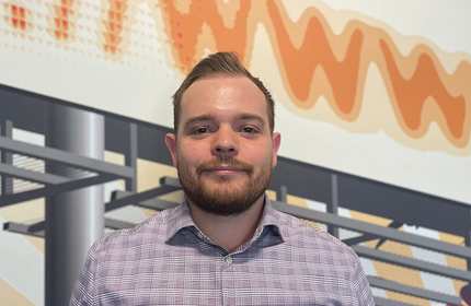 Headshot of a person in front of a large poster