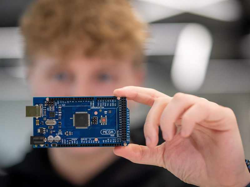 A person holds a micro-controller circuit board.