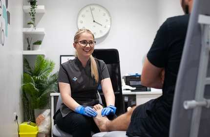 A podiatry student assesses the foot of a patient