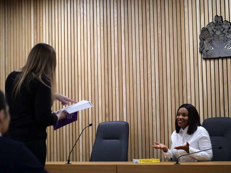 A person stands facing a courtroom bench.