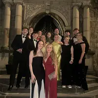 A group of people in formal attire smiling and posing together for a photo at a social event.