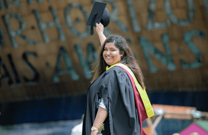 Cardiff Met student raising a graduation cap above their head