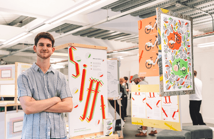 A man stands in front of a colorful display of various posters, examining the artwork and information presented.