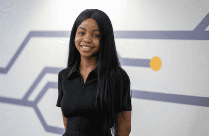 Elizabeth Aluko sits at a desk in one of the commonspaces on the Cardiff Met campus, working from a laptop